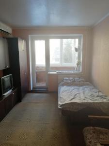 a bedroom with a bed and a large window at Квартира in Sumy