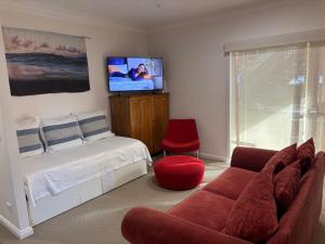a bedroom with a bed and a couch and a tv at Family stay minute walk from Hargraves beach in Norah