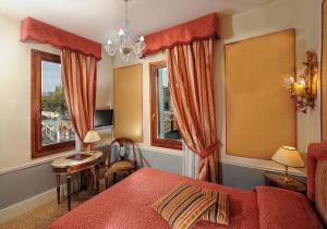 a bedroom with a red bed and two windows at Hotel Arlecchino in Venice