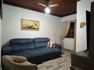 a living room with a blue couch and a ceiling fan at Mara e Jorge Suites Beira Mar in Cananéia