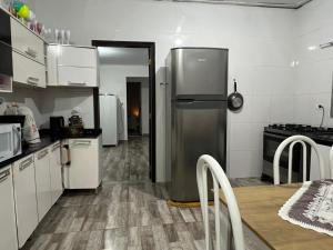 a kitchen with a stainless steel refrigerator and a table at Mara e Jorge Suites Beira Mar in Cananéia