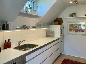 a white kitchen with a sink and a refrigerator at Charming House With A View Of The Sea in Båring