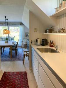 a kitchen with a sink and a dining room at Charming House With A View Of The Sea in Båring