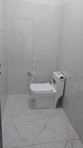 a bathroom with a toilet in a white wall at Abidharpp in Velankanni