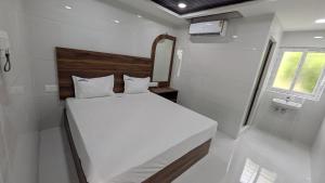 a small bedroom with a white bed and a window at Abidharpp in Velankanni