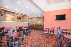 a restaurant with tables and chairs and a flat screen tv at Days Inn by Wyndham Joplin in Joplin