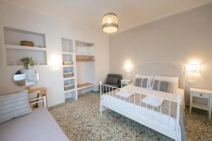 a bedroom with a white bed and a chair at Sunny yard apartments in Poros