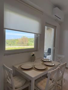 a dining room table with two chairs and a window at Maison Soleil II in Kastro Kyllini