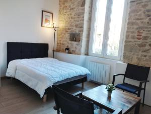 a bedroom with a bed and a table and a chair at studio moderne les pieds dans l'eau in Larmor-Baden
