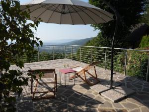 a patio with an umbrella and a table and chairs at Vineyard cottage SkyView in Semič +3 photos