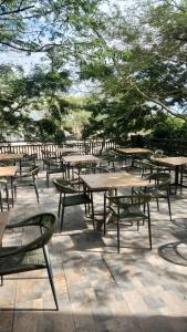 a group of tables and chairs with trees in the background at The Ivy Hotel in Lusaka