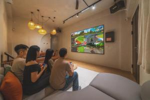 a group of people sitting in a room playing a video game at Tainan Sunwood B&B in Anping