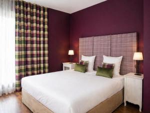 a bedroom with a large bed with purple walls at Hôtel Restaurant Verger des Châteaux, Route des vins Haut-Koenigsbourg in Dieffenthal
