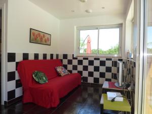 a living room with a red couch and a checkered wall at Gîte de Roques in Serres-sur-Arget