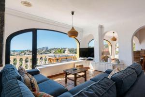 a living room with a blue couch and a large window at Robis Moraira in Benissa