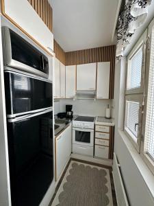 a small kitchen with a black refrigerator and white cabinets at Pohjankaira in Rovaniemi
