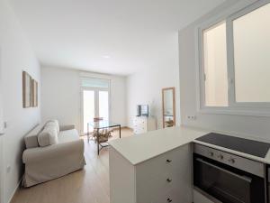 a white kitchen with a white counter and a chair at Apartamento Calle Bolsa in Sanlúcar de Barrameda