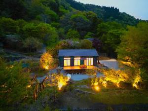 Draufsicht auf ein kleines Haus mit Lichtern im Gras in der Unterkunft HighLand 伊豆大島箱根連峰を望む高級貸切ヴィラサウナ大型ウッドデッキ薪ストーブ完備 in Arashi