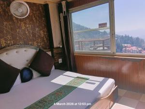 a bedroom with a bed and a window with a view at New Malook hotel in Shimla