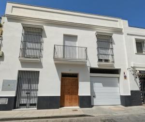 a white house with a brown door at Apartamento Calle Bolsa in Sanlúcar de Barrameda