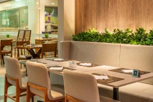 a restaurant with tables and chairs and a plant at Hotel Laghetto Pedras Altas in Gramado +78 photos