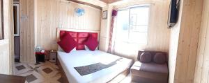 a bedroom with a bed with red pillows and a chair at New Malook hotel in Shimla