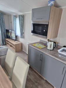 a room with a kitchen with two white chairs at Sharmar Eyemouth in Eyemouth