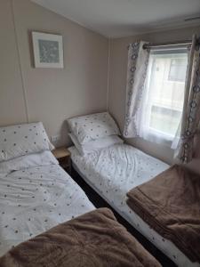 two twin beds in a bedroom with a window at Sharmar Eyemouth in Eyemouth +1 photo