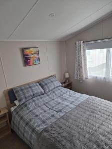 a bedroom with a bed with a blue comforter and a window at Sharmar Eyemouth in Eyemouth