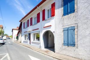 a white building with red and blue windows on a street at Chambres D'hôtes Madan'hôte in Capbreton