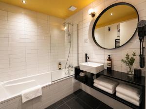 a bathroom with a tub and a sink and a mirror at Hôtel Restaurant Vaillant -ouverture Spa de 1200m2 Octobre 2026 in Sélestat