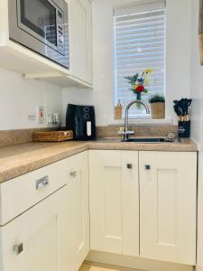 a kitchen with white cabinets and a sink and a microwave at 1 Bed Flat - Sleeps 2 - Parking - Garden in Derry Londonderry