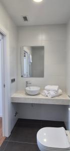 a white bathroom with a sink and a toilet at Pensión Agro da Porta in Palas de Rei