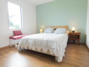a bedroom with a white bed and a red chair at Le gîte de la battère in Saubusse