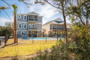 a house with a fence and a pool at Beach 45 by Oak Island Accommodations in Oak Island