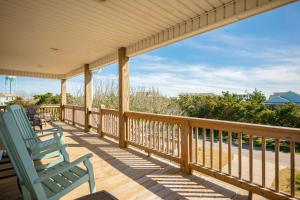 a porch with two blue rocking chairs on it at Beach 45 by Oak Island Accommodations in Oak Island
