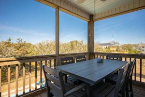 a porch with a table and chairs on a balcony at Beach 45 by Oak Island Accommodations in Oak Island +99 photos
