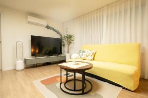 a living room with a yellow couch and a tv at Banghwa Space 5 min to Banghwa Stn, Near Gimpo Airport, Magok & COEX in Seoul
