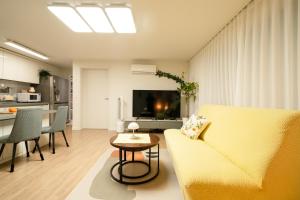 a living room with a yellow couch and a table at Banghwa Space 5 min to Banghwa Stn, Near Gimpo Airport, Magok & COEX in Seoul