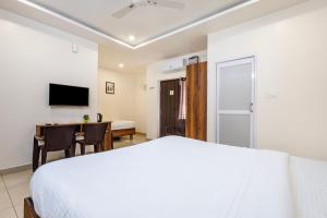 a bedroom with a bed and a desk and a television at Cannan Residency Pondicherry in Pūrnānkuppam