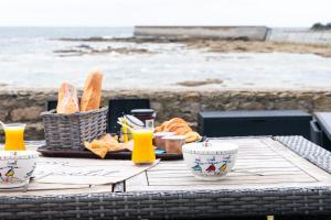 a picnic table with a basket of bread and orange juice at La Rose des Sables in Tréffiagat