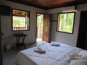 a bedroom with a bed and a table and two windows at Pousada Alto do Bau in Conceição do Mato Dentro +47 photos