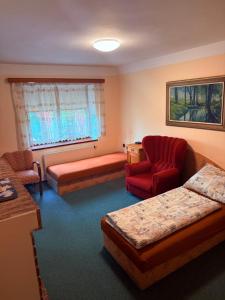 a living room with two beds and a red chair at Rodinný Penzion U Nouzů in Staré Hradiště +38 photos