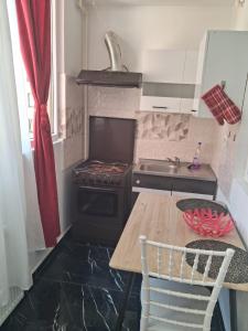 a small kitchen with a stove and a wooden table at Modern 1-Bedroom Apartment with AC, Free Parking & Self Check-in Bucharest-Militari in Dudu