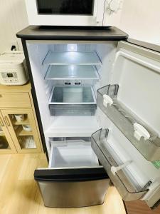 an empty refrigerator with its door open in a kitchen at つんまぁー家 in Miyakojima