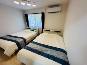 two beds in a small room with a window at つんまぁー家 in Miyakojima