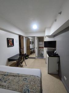 a hotel room with a bed and a desk and a table at Ralph Anthony Suites Hotel in Manila