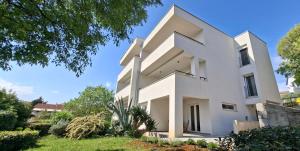 a large white house with trees in front of it at Apartments Daria in Krk