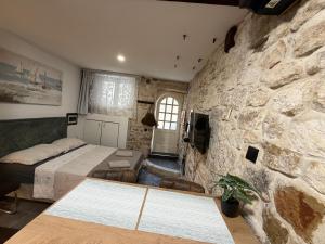 a bedroom with a stone wall and a bed at Dragazzo studio in Trogir