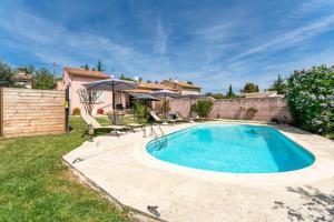 a swimming pool in a yard with chairs and umbrellas at Maison proche Vaison la Romaine in Saint-Romain-en-Viennois